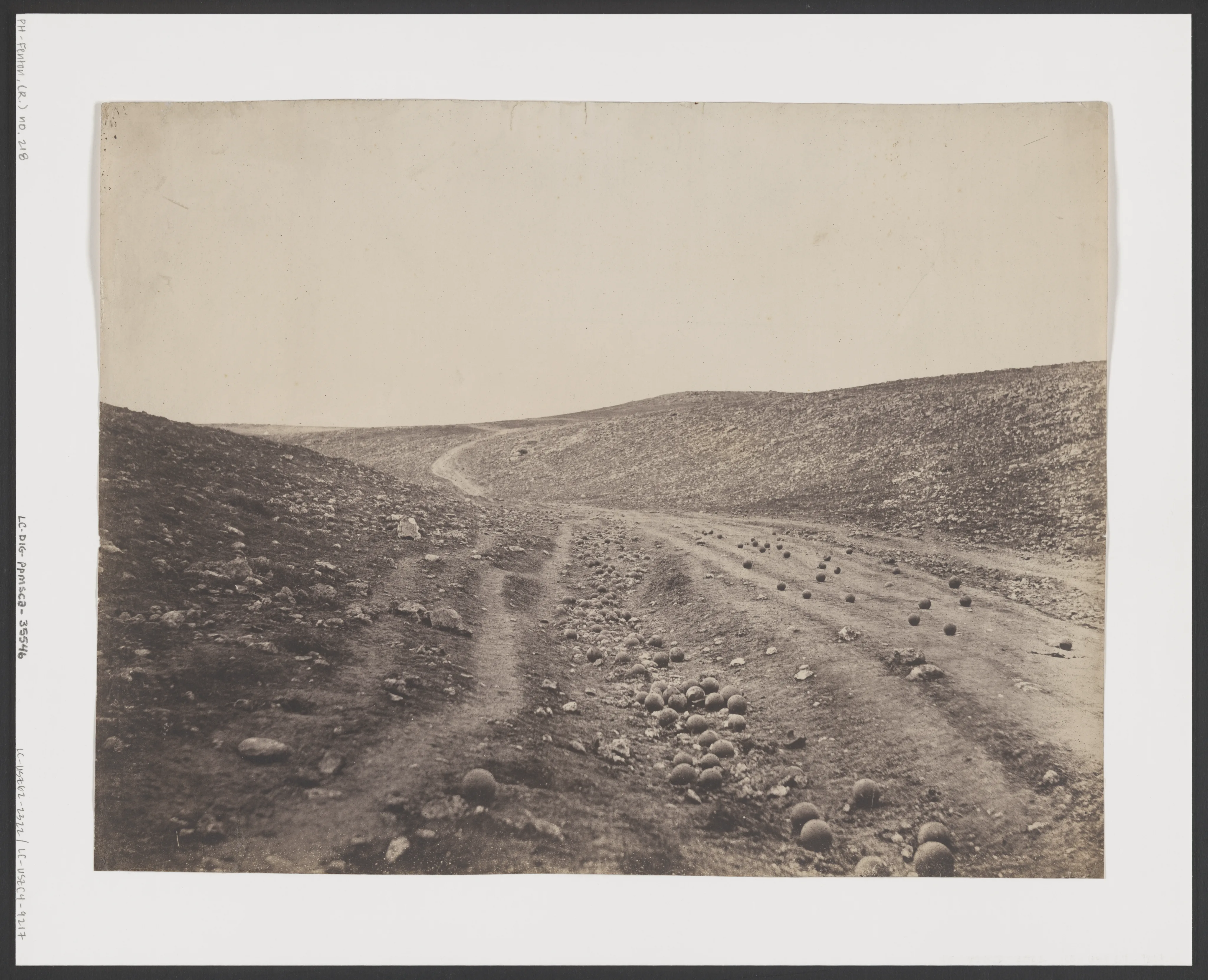 A dirt road through a ravine, with cannonballs scattered on the roadway.